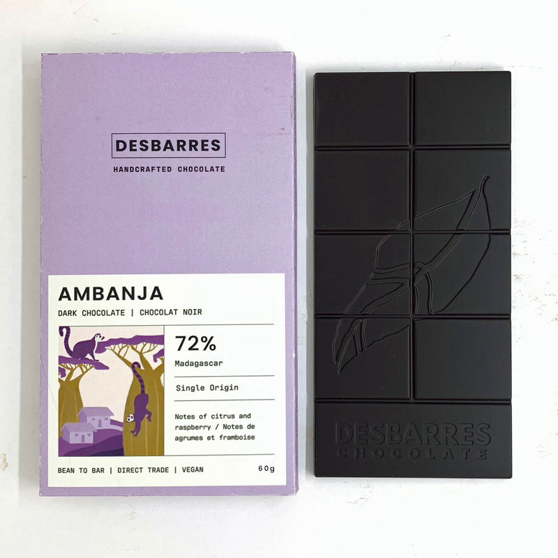 A Desbarres Ambanja 72% Dark Chocolate bar and its lavender packaging are shown side by side. The packaging features purple lemurs in trees and the chocolate bar has an embossed leaf design.