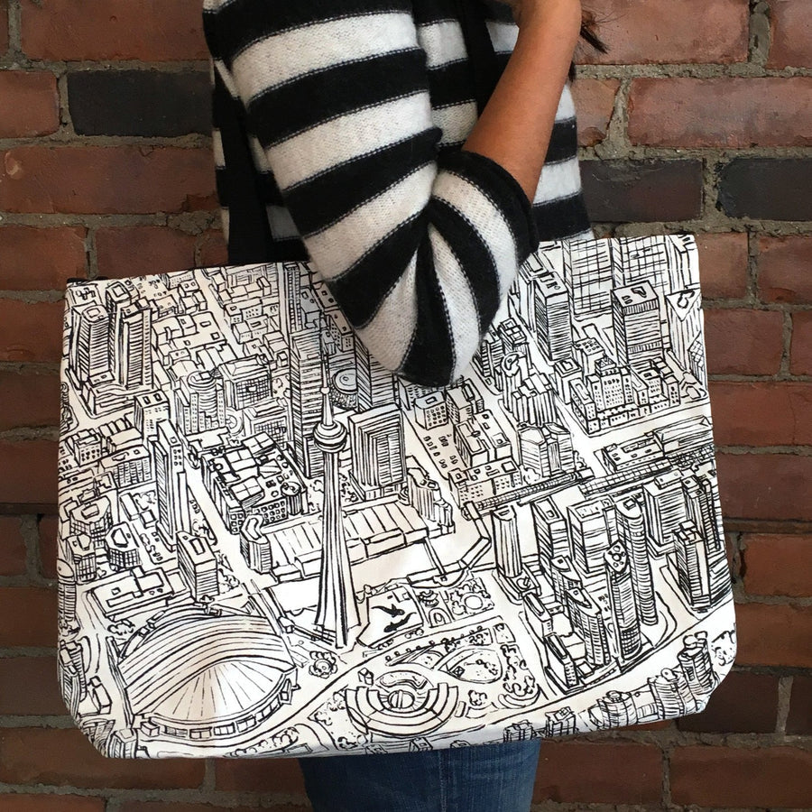 A black and white tote bag with a hand-drawn map of Toronto, featuring the CN Tower and City Hall.