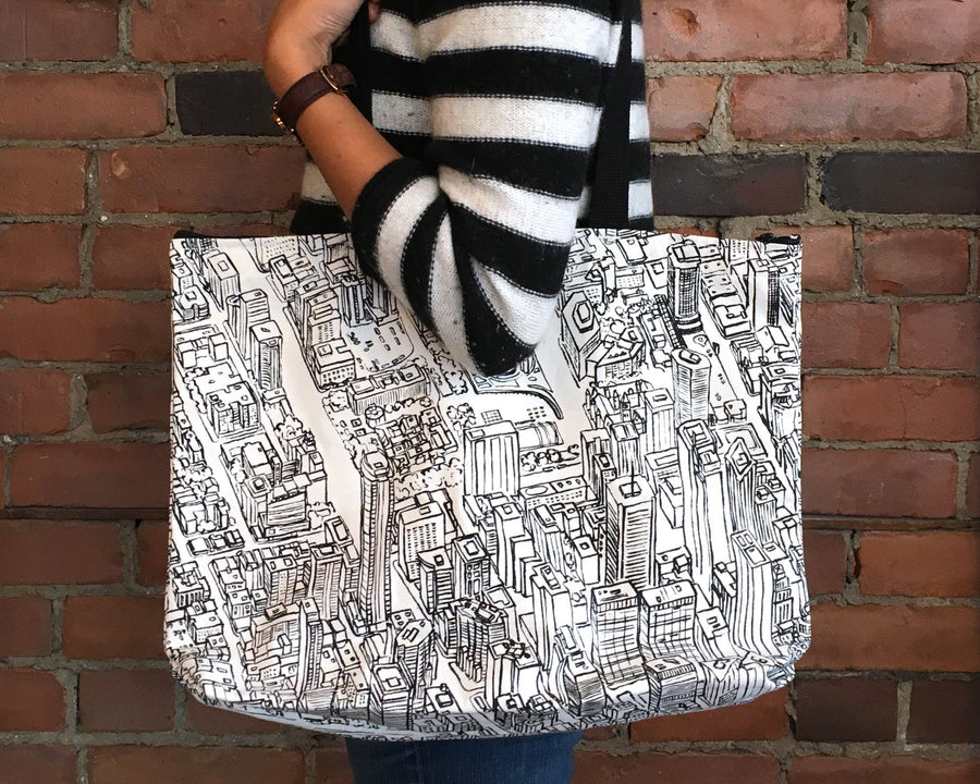 A black and white tote bag with a hand-drawn map of Toronto, featuring the CN Tower and City Hall.
