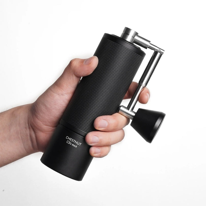 Hand holding a Timemore black coffee grinder with 'Chestnut' branding on a white background