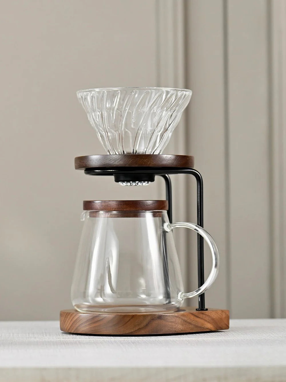 Glass coffee maker with wooden base on a neutral background