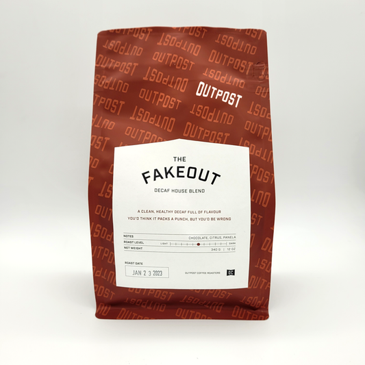 A packaged bag of 'The Fakeout' decaf coffee from Outpost Coffee with branding and product information displayed on the front.